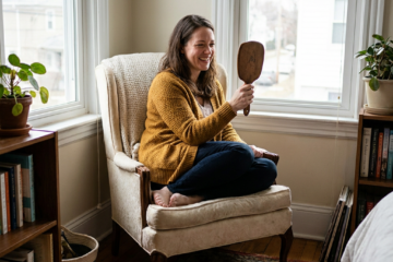 Abigail checks her confident, healthy smile in a hand mirror in a bedroom reading nook.